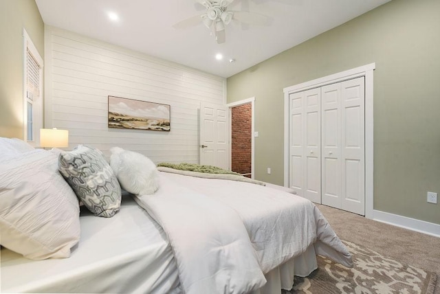 carpeted bedroom featuring wood walls, ceiling fan, and a closet