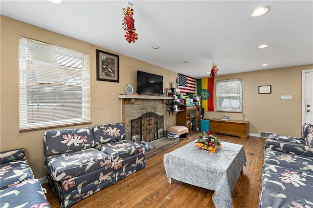 living room with a stone fireplace and hardwood / wood-style floors