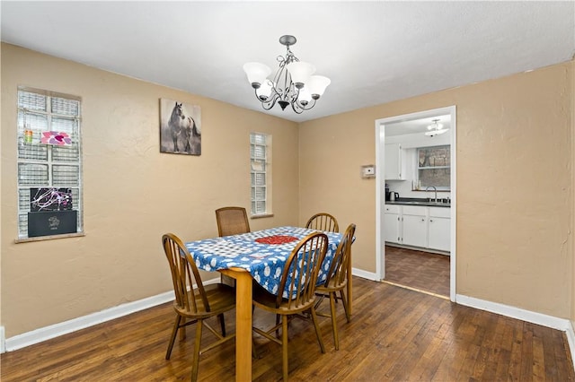 dining space featuring sink, dark wood-type flooring, and a chandelier