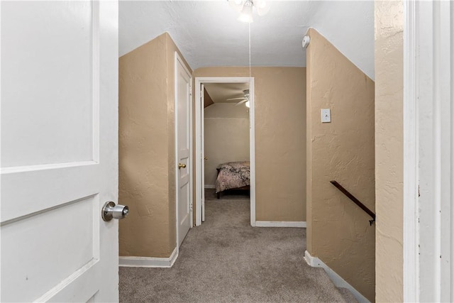 corridor with lofted ceiling and carpet