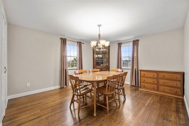 dining space with dark wood-type flooring and a notable chandelier