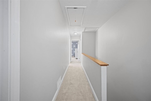 hallway featuring light colored carpet and a textured ceiling