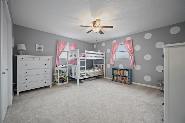 carpeted bedroom featuring ceiling fan and a textured ceiling