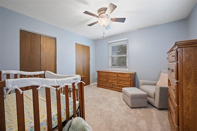 carpeted bedroom with two closets and ceiling fan