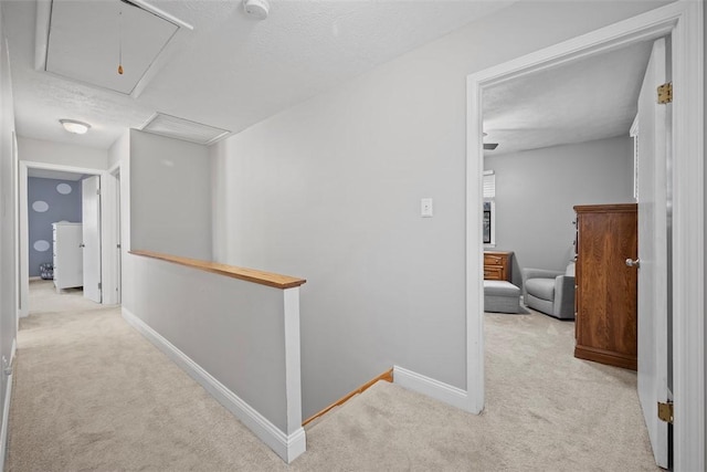 hallway with light colored carpet and a textured ceiling