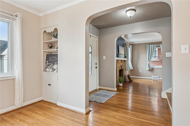 entryway with ornamental molding and hardwood / wood-style floors