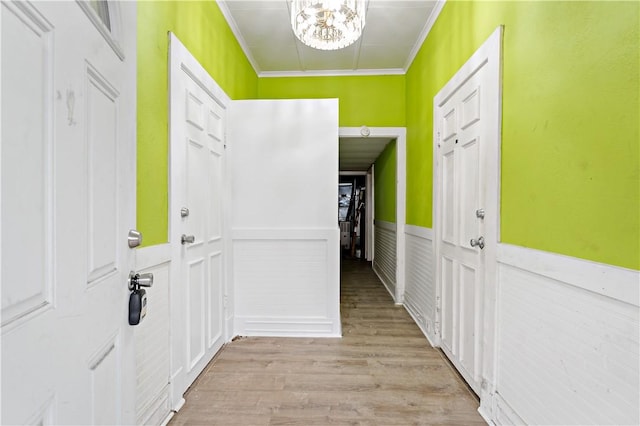 entryway with ornamental molding, a chandelier, and light wood-type flooring