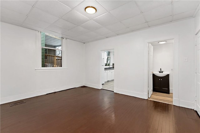 empty room featuring dark hardwood / wood-style flooring, sink, and a drop ceiling