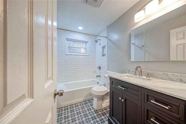 full bathroom featuring tile patterned flooring, vanity, tiled shower / bath, and toilet