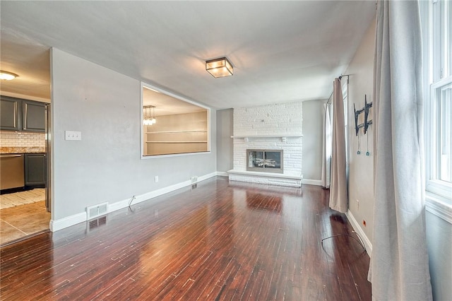 unfurnished living room with a stone fireplace and dark hardwood / wood-style flooring