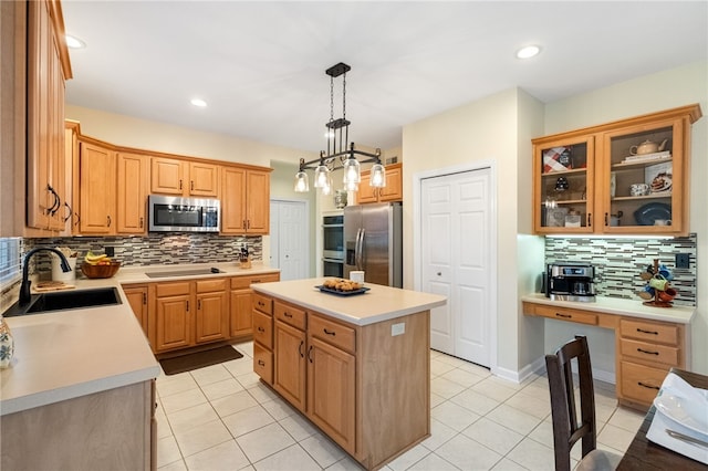 kitchen with a kitchen island, appliances with stainless steel finishes, built in desk, sink, and hanging light fixtures