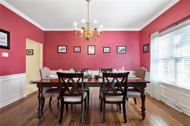 dining room featuring ornamental molding, hardwood / wood-style floors, and a notable chandelier