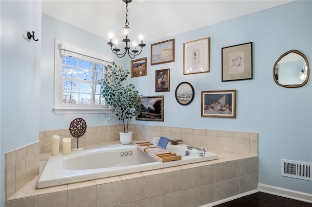 bathroom with a relaxing tiled tub and a notable chandelier