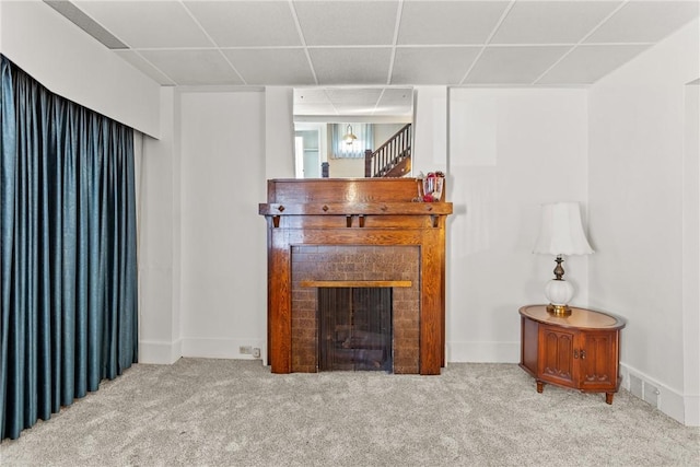 carpeted living room with a paneled ceiling and a fireplace