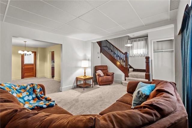 living room featuring carpet, a paneled ceiling, and an inviting chandelier