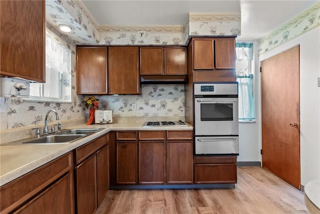 kitchen with stainless steel oven, white gas stovetop, light hardwood / wood-style floors, and sink