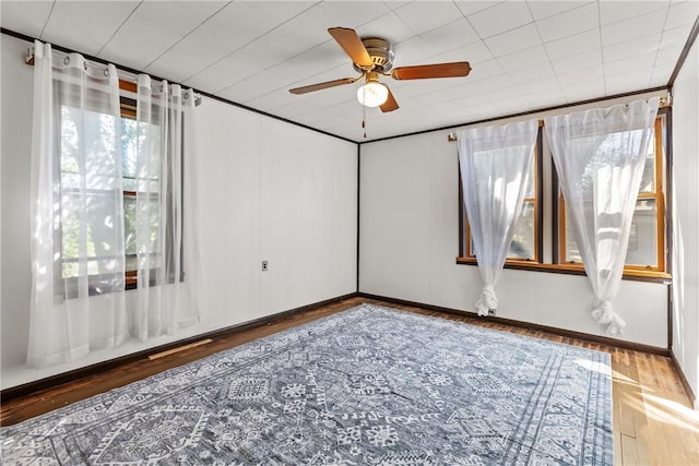 empty room featuring hardwood / wood-style flooring, ceiling fan, and ornamental molding