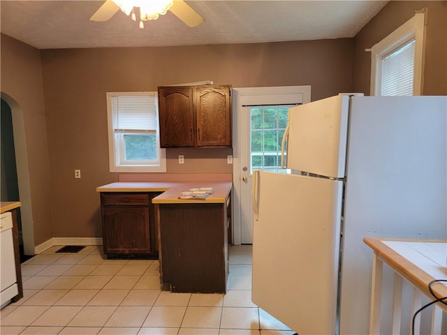 kitchen with white refrigerator, ceiling fan, dark brown cabinets, and light tile patterned floors