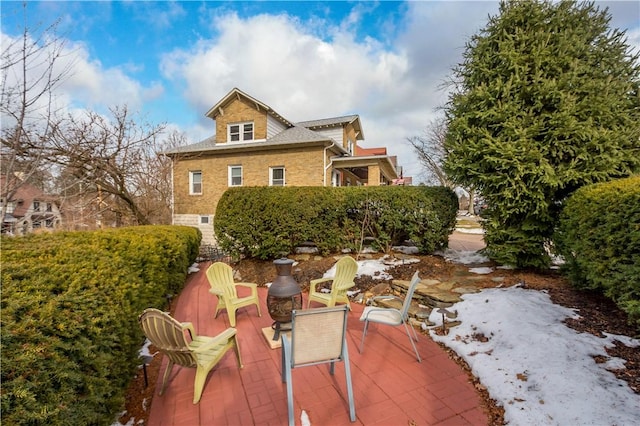 snow covered rear of property with a patio