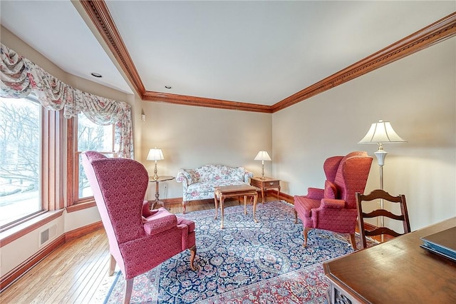 living area featuring crown molding and light hardwood / wood-style floors