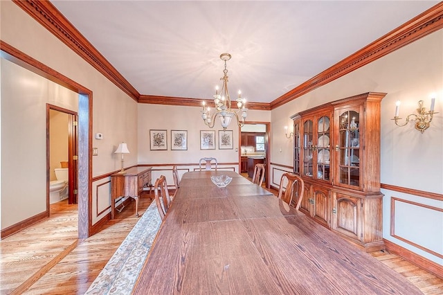 dining area featuring crown molding, an inviting chandelier, and light hardwood / wood-style flooring