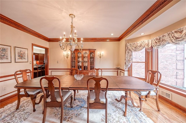 dining space featuring crown molding, a chandelier, and light hardwood / wood-style flooring