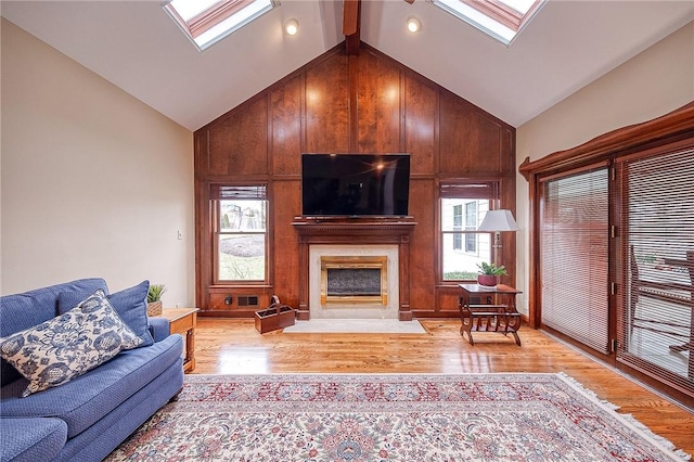 living room featuring a large fireplace, a skylight, and light hardwood / wood-style floors