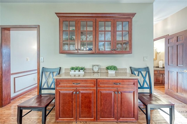 bar with light stone countertops and light wood-type flooring