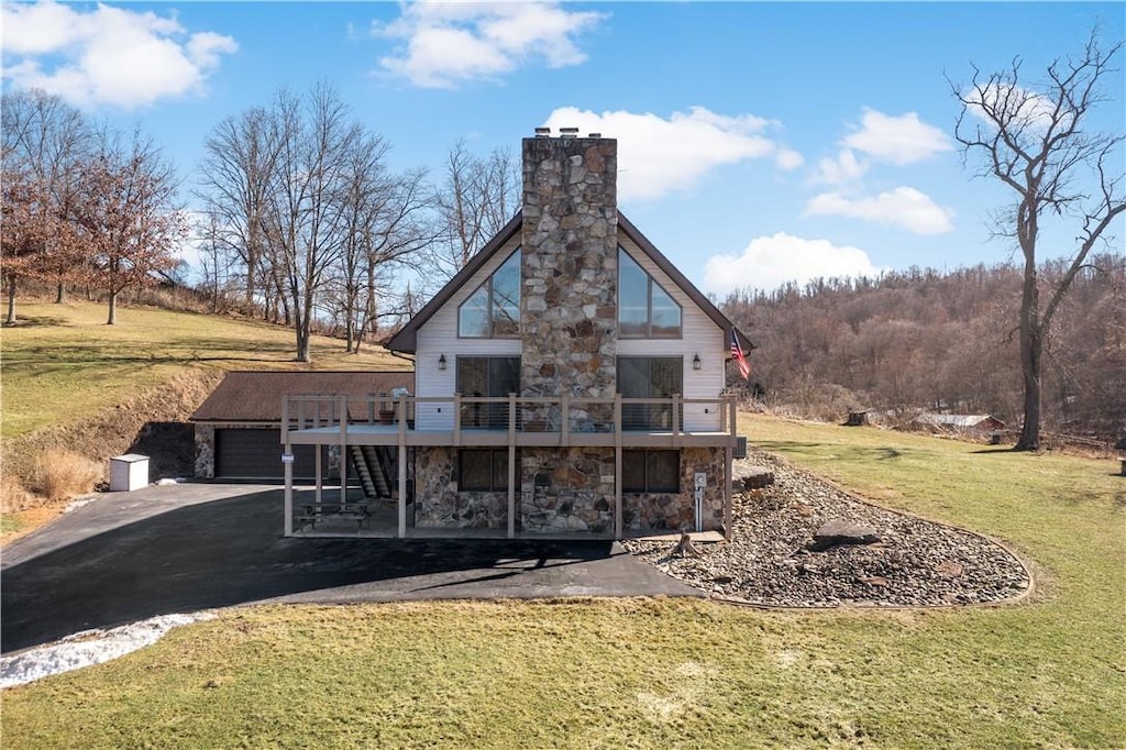 back of property with a garage, a deck, and a lawn