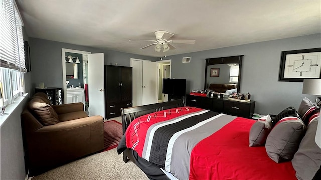 carpeted bedroom with multiple windows, ensuite bath, and ceiling fan