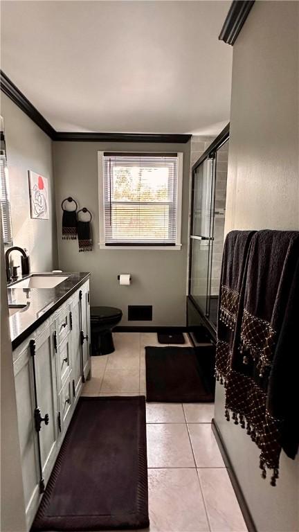 bathroom featuring tile patterned flooring, vanity, ornamental molding, an enclosed shower, and toilet