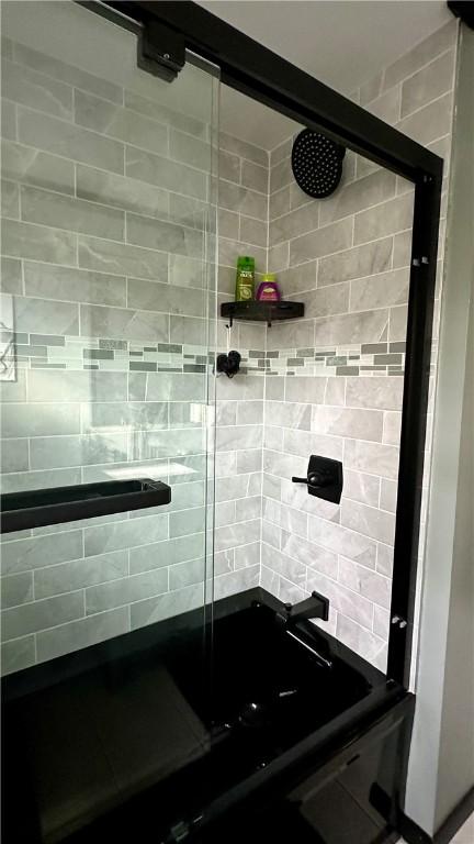 bathroom with backsplash and a shower with shower door