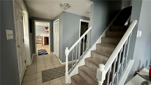 stairs with tile patterned floors and a fireplace