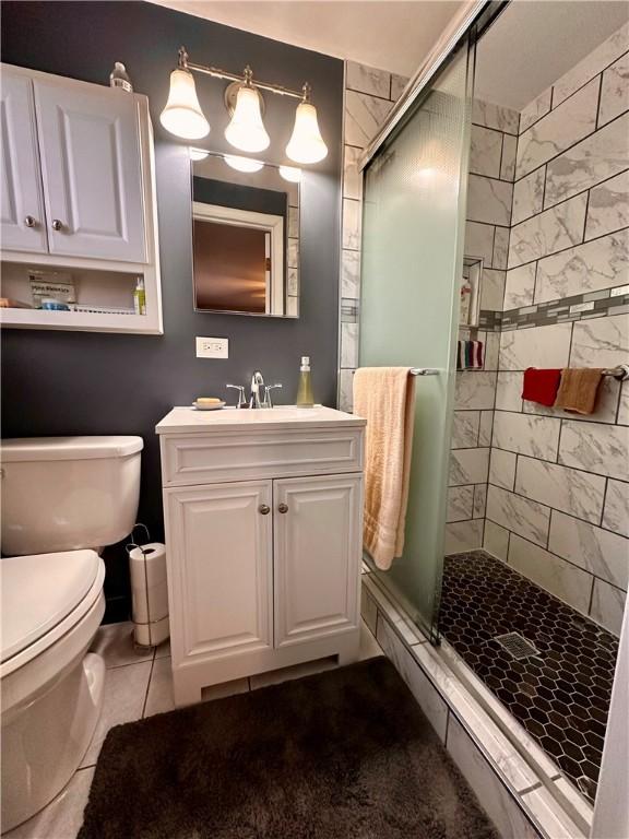 bathroom with vanity, toilet, an enclosed shower, and tile patterned flooring