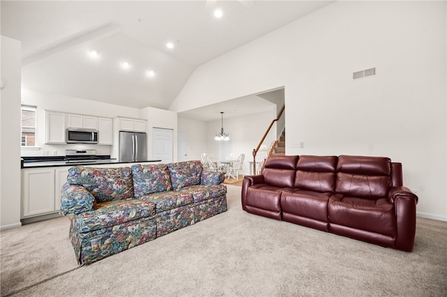 living room featuring light carpet, a notable chandelier, and high vaulted ceiling