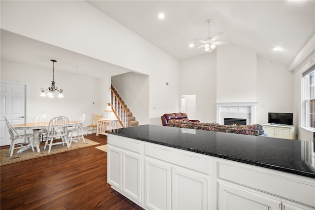 kitchen with vaulted ceiling, dark hardwood / wood-style floors, ceiling fan with notable chandelier, decorative light fixtures, and white cabinets