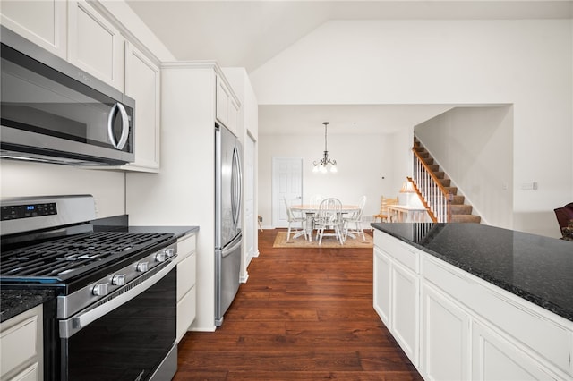 kitchen with lofted ceiling, appliances with stainless steel finishes, dark hardwood / wood-style floors, white cabinets, and dark stone counters