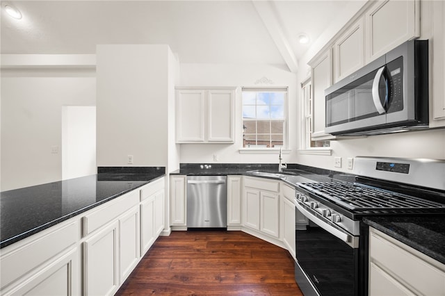 kitchen with white cabinetry, stainless steel appliances, sink, and dark stone counters