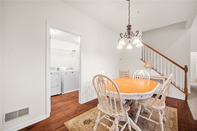 dining area with dark wood-type flooring, washing machine and clothes dryer, and a chandelier