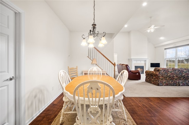 dining room with ceiling fan with notable chandelier, vaulted ceiling, and dark hardwood / wood-style floors