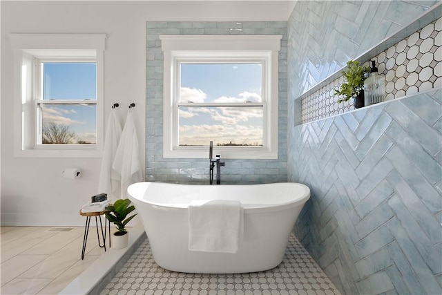 bathroom featuring a tub to relax in, tile patterned flooring, and tile walls