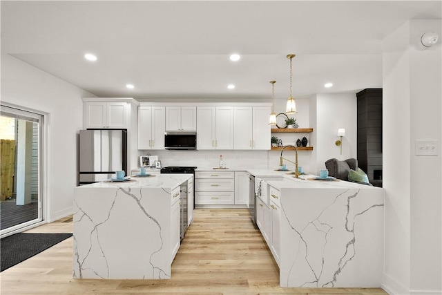 kitchen with decorative light fixtures, tasteful backsplash, white cabinetry, light stone counters, and stainless steel appliances