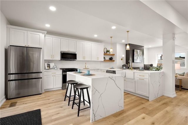 kitchen with appliances with stainless steel finishes, decorative light fixtures, a center island, and white cabinets