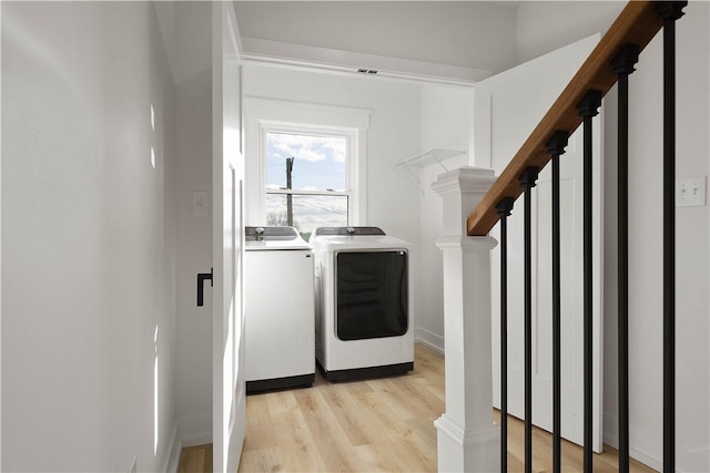 laundry area with washer and clothes dryer and light hardwood / wood-style floors