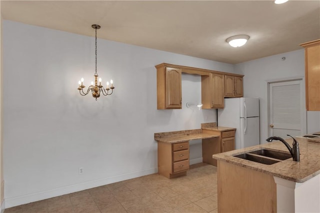 kitchen featuring decorative light fixtures, sink, white refrigerator, kitchen peninsula, and light stone countertops