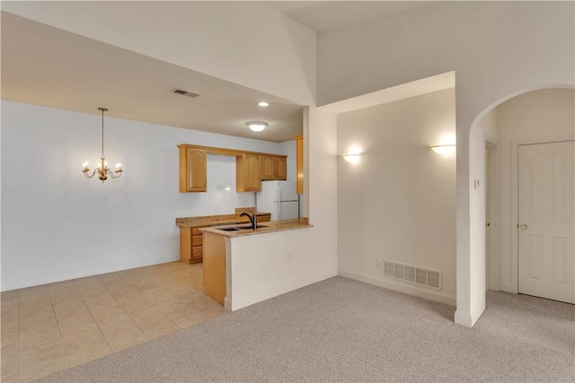 kitchen with sink, decorative light fixtures, white refrigerator, kitchen peninsula, and light colored carpet