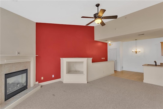 unfurnished living room with ceiling fan with notable chandelier, lofted ceiling, light carpet, and a tile fireplace