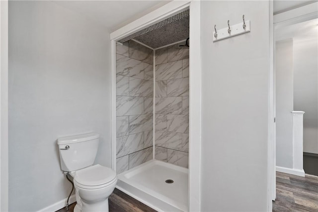 bathroom featuring a tile shower, wood-type flooring, and toilet