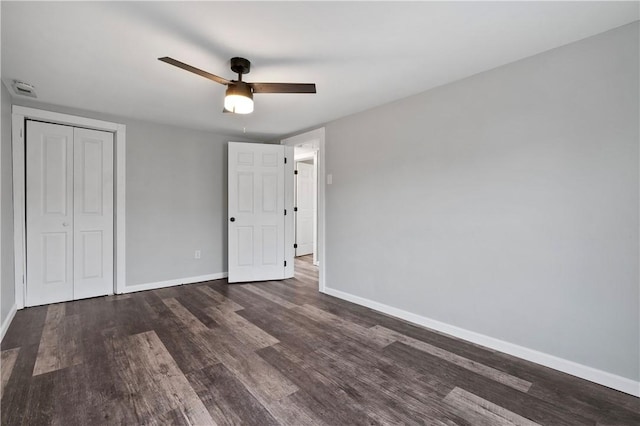 unfurnished bedroom with ceiling fan, dark hardwood / wood-style flooring, and a closet