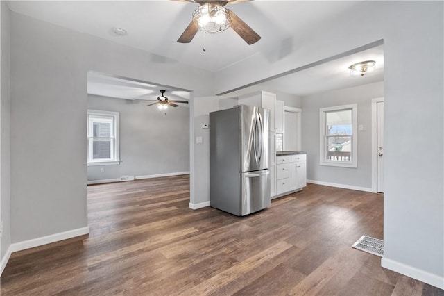 kitchen with stainless steel fridge, dark hardwood / wood-style flooring, and white cabinets